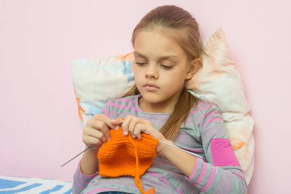 The girl knits on spokes sitting on the bed — Stock Photo, Image