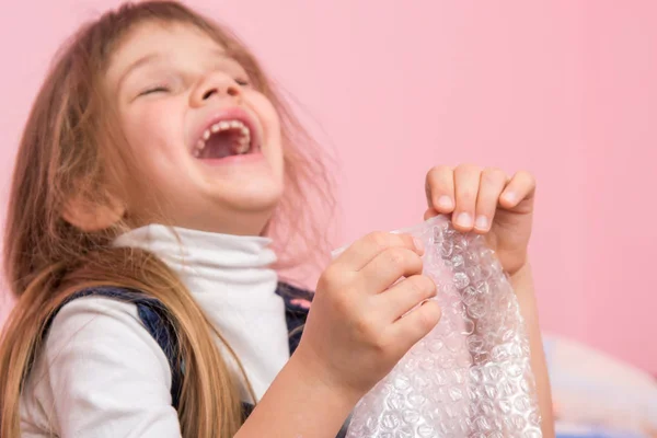 The girl laughs infectiously, playfield balls on the packaging bag — Stock Photo, Image