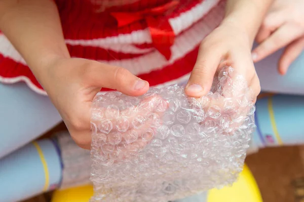 Вид зверху на руки дитини, натискаючи на бульбашки на пакувальній плівці — стокове фото