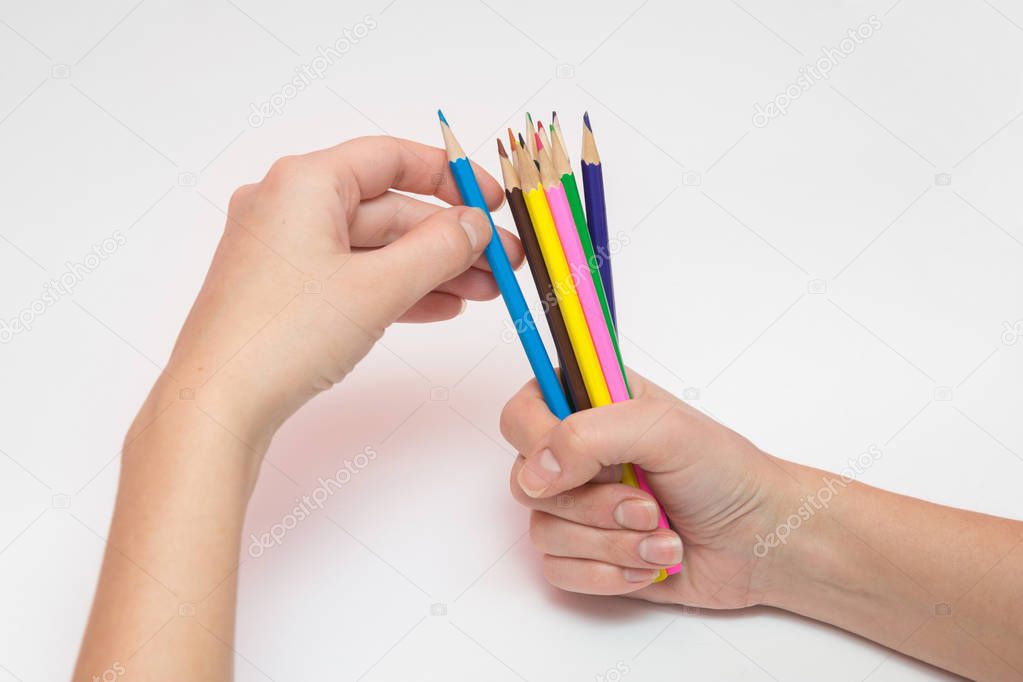 Female hand holding a fist around a dozen pencils, the other hand selects the desired color