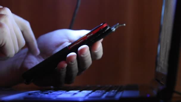 Manos escribiendo en su teléfono inteligente que trabaja en un ordenador portátil, primer plano — Vídeo de stock