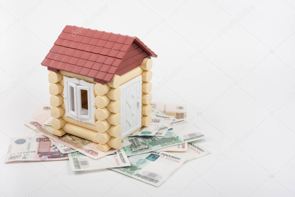 House stands on the banknotes of Russian rubles, from the roof sticking out of ten US dollars banknote