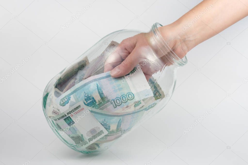 Hand takes out a three-liter glass jars thousand Russian rubles