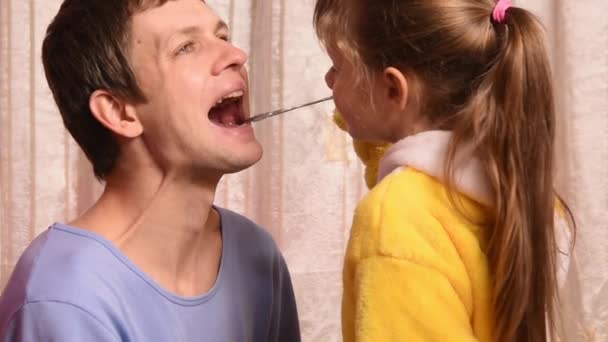 La fille de cinq ans jouant au docteur avec papa regardait la gorge, le nez et les oreilles, puis montrant les pouces à papa en bonne santé — Video