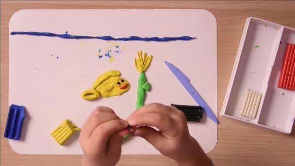 Kind beeldhouwt uit plasticine handen eens en ambachten element naleplyaet het op de plaat, close-up, bovenaanzicht — Stockvideo