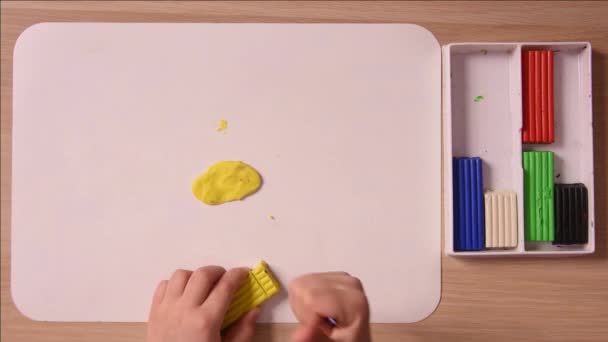 L'enfant coupe un morceau d'une pile de plasticine jaune pour l'artisanat, gros plan, vue du dessus — Video