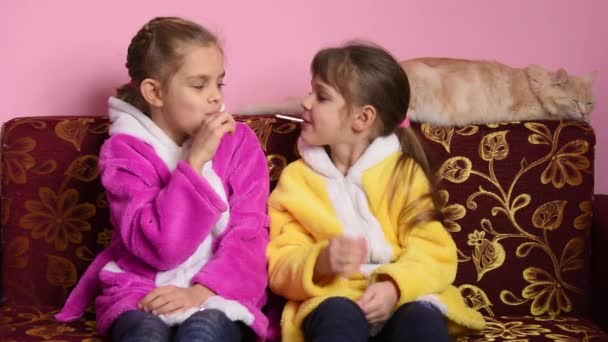 Chica divertida en la boca con sus piruletas jugando con palos que salen de su boca — Vídeos de Stock