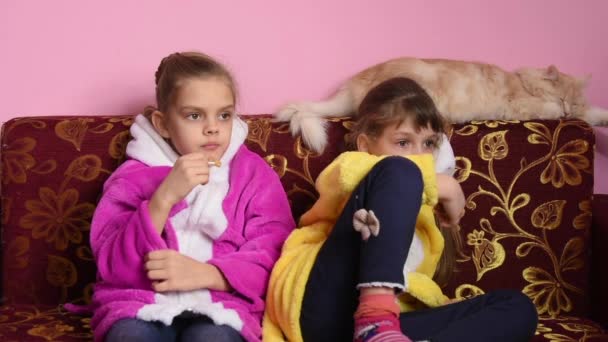 Duas meninas sentadas no sofá e assistindo TV entusiasticamente — Vídeo de Stock