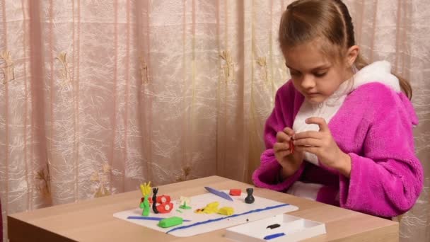 Chica esculpe artesanías de plastilina sentado en una mesa en el otro lado del espacio vacío bajo el título — Vídeos de Stock