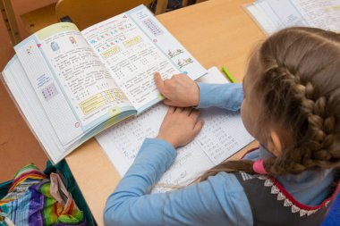 Anapa, Rusya Federasyonu - 28 Şubat 2017: Birinci sınıf öğrencisi görev parmağını metnin altında çalışan ders kitabı okur