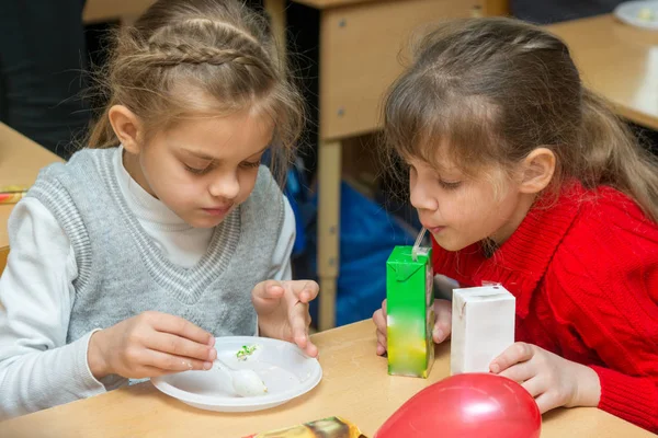 Two children are drinking juice and eating cake at a party at school — Stock Photo, Image