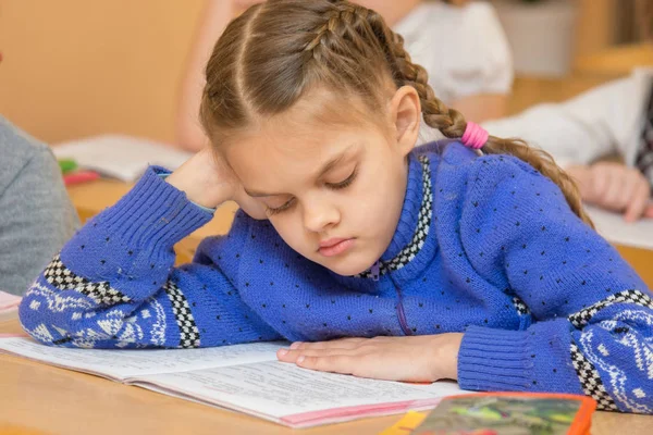 Första grader vid behandlingen lektion läsa text som sitter vid en skolbänk — Stockfoto