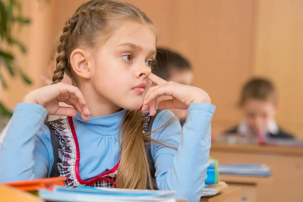 A menina em uma lição na escola colhendo seu nariz — Fotografia de Stock