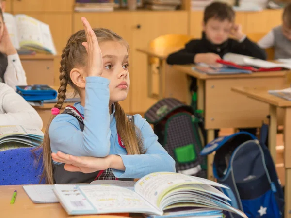 Menina estudante em uma lição na escola querendo puxar a mão para cima para responder a uma pergunta — Fotografia de Stock