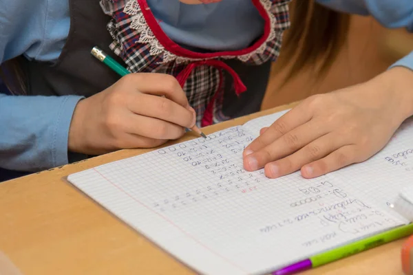 Första-grader på en lektion matematik skriver i notebook, närbild — Stockfoto