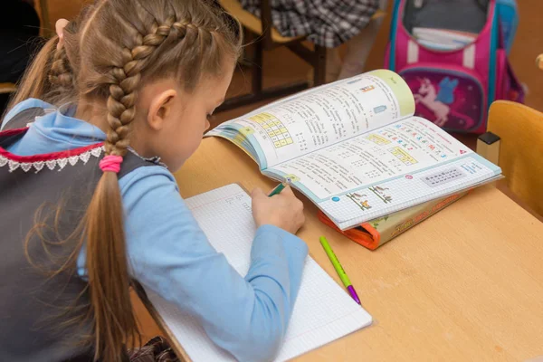 Anapa, Russia - 28 febbraio 2017: La prima elementare a una lezione di matematica scrive in un quaderno, vista laterale dal retro — Foto Stock