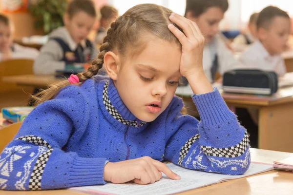 Ein Erstklässler liest Zeile für Zeile mit einem Finger vor, im Hintergrund andere Schüler — Stockfoto