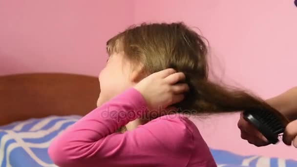 Dziewczyna jest bardzo boli, gdy mama grzebienie jej splątane włosy — Wideo stockowe