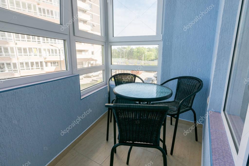 A table and three chairs on the balcony in the apartment of a multistory apartment building
