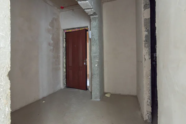 Вход в квартиру - новостройка, входная дверь и голые бетонные и обшарпанные стены. — стоковое фото