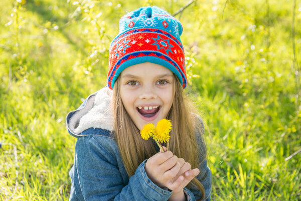 Seven-year-old girl in the spring is pleased with the blossoming dandelions