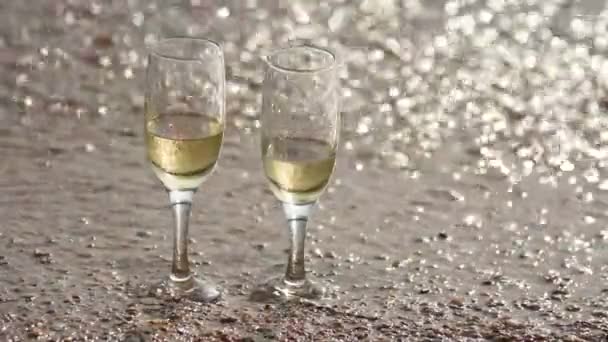 Dalga Yıkanmış Uzakta Iki Bardak Şampanya Sahilde Kum Üzerinde Duran — Stok video