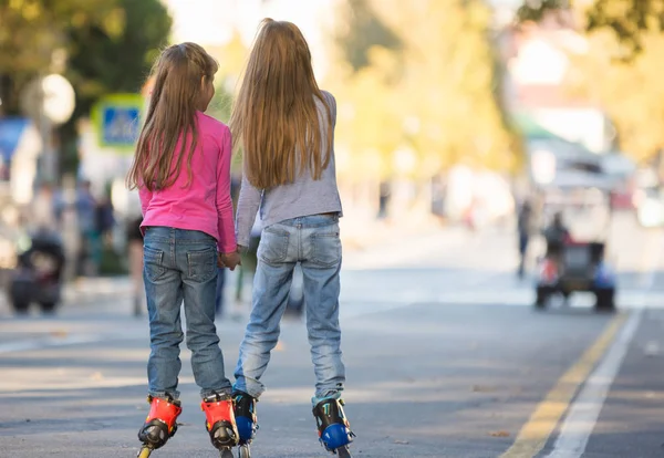 Two girls girlfriends rollerblading on the mall, rear view — Stock Photo, Image