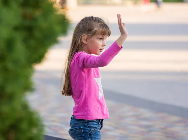 Menina de seis anos acenando com a mão, vista lateral — Fotografia de Stock