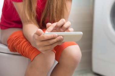 Çocuğun tuvalete oturuyor ve telefonda çalış