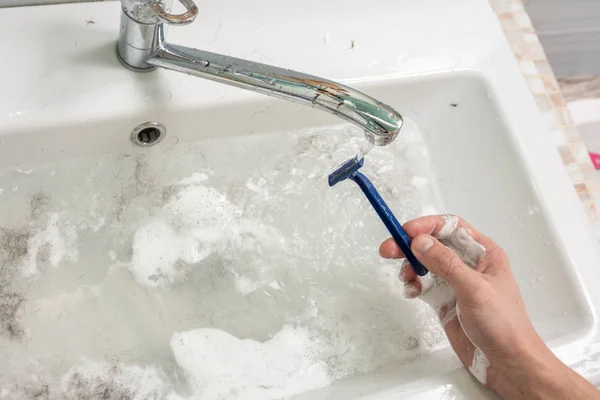 La mano del hombre lava la máquina de afeitar bajo el chorro de agua — Foto de Stock