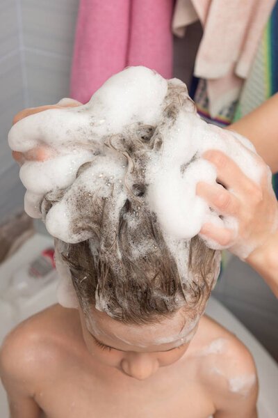 Mum soaps the baby's long hair with shampoo