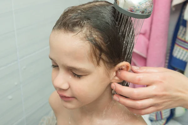 Mom washes the baby's ear under the shower — Stockfoto