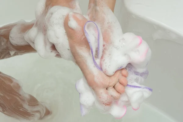 Мама миє ноги дитини мочалкою і милом — стокове фото