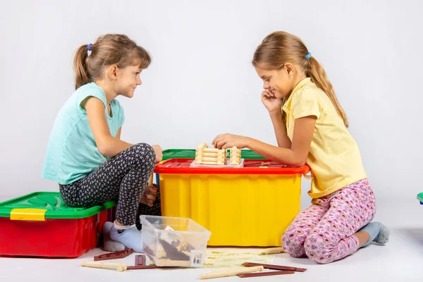 Duas meninas coletam uma casa em uma caixa com brinquedos — Fotografia de Stock