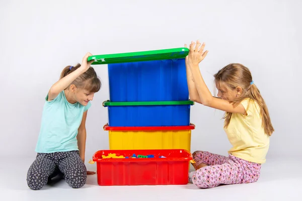 Två flickor öppnade locket på en stor plastlåda med leksaker, och titta inuti — Stockfoto