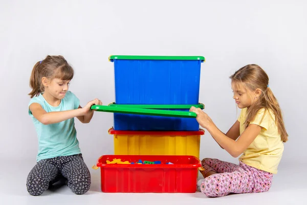 Две девушки открыли большой пластиковый ящик с игрушками — стоковое фото