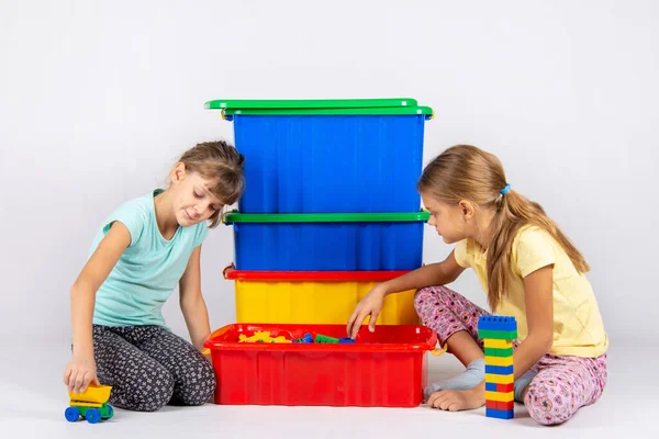 Two girls opened a box with a designer and start to play toys — Stock Photo, Image