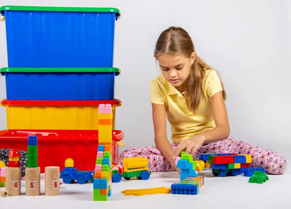 Tioårig flicka som leker leksaker sittande på golvet — Stockfoto