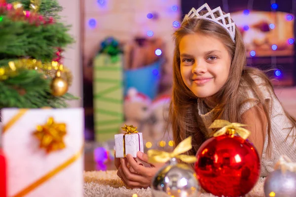 Chica sosteniendo un pequeño regalo bonito en sus manos, y mira en el marco —  Fotos de Stock