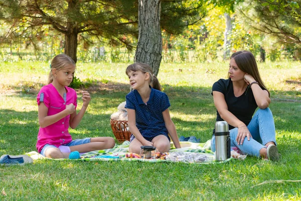Две девушки и девушка разговаривают на пикнике — стоковое фото
