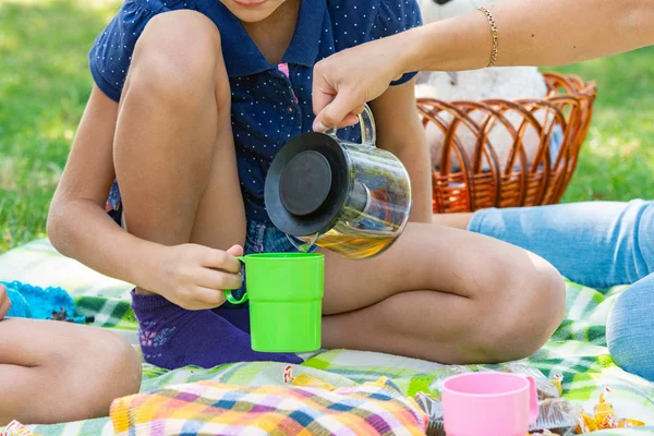 Närbild som en flicka häller te i en tonårings koppar på en picknick i parken — Stockfoto