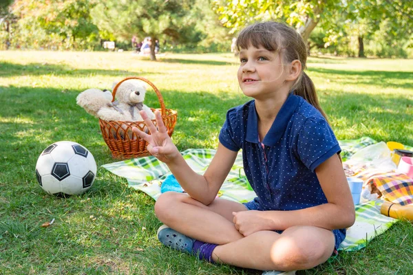 Girl on a picnic counts goals scored on fingers — ストック写真
