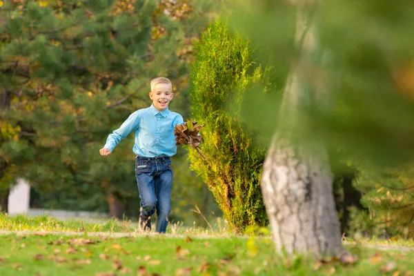 Мальчик счастливо бежит по парку на зеленой траве — стоковое фото