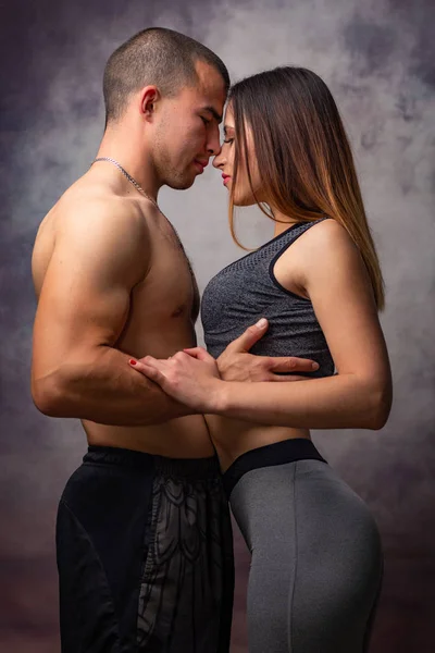 Joven pareja amorosa de abrazos de físico atlético sobre fondo gris — Foto de Stock