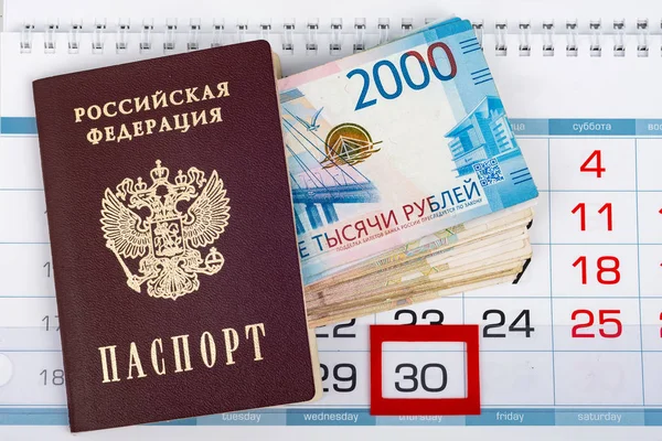 Паспорт і велика зграя російських рублів знаходяться в календарі з виділеним номером 30. — стокове фото
