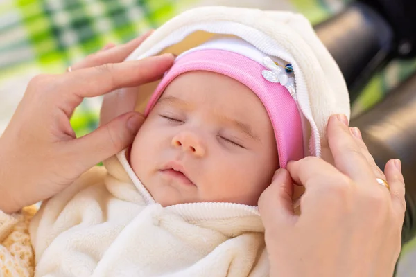 Mom fixes the cap of a two-month-old baby — 스톡 사진