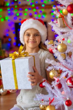 Beautiful girl with a big New Year's gift against the background of blurred lights