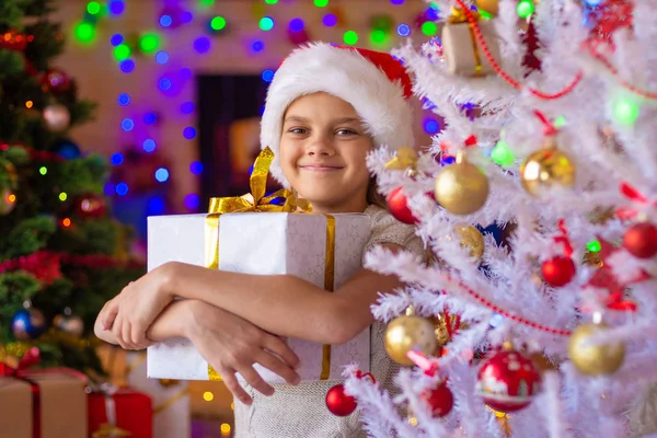 Feliz chica hermosa con un regalo en un árbol de Navidad blanco —  Fotos de Stock