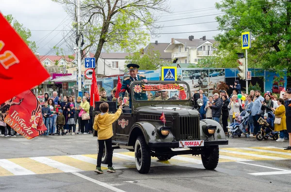 Anapa, Rusia - 9 de mayo de 2019: Los niños dan flores a los veteranos que conducen un automóvil militar restaurado en el desfile de la victoria en Anapa — Foto de Stock