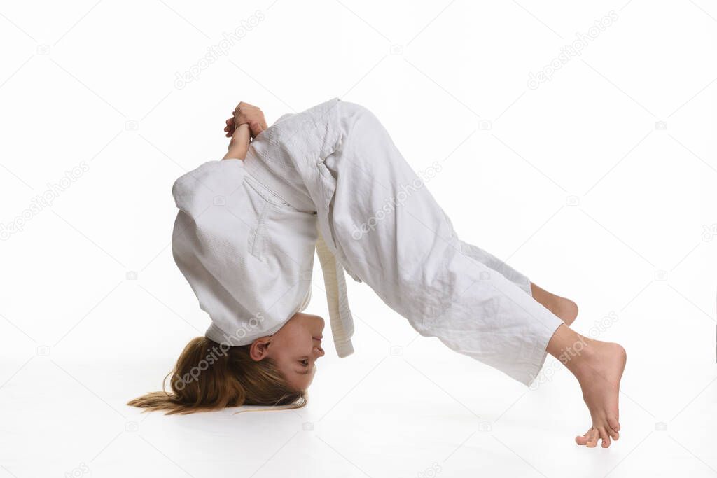 Girl judo student performs exercise sticking to head and legs